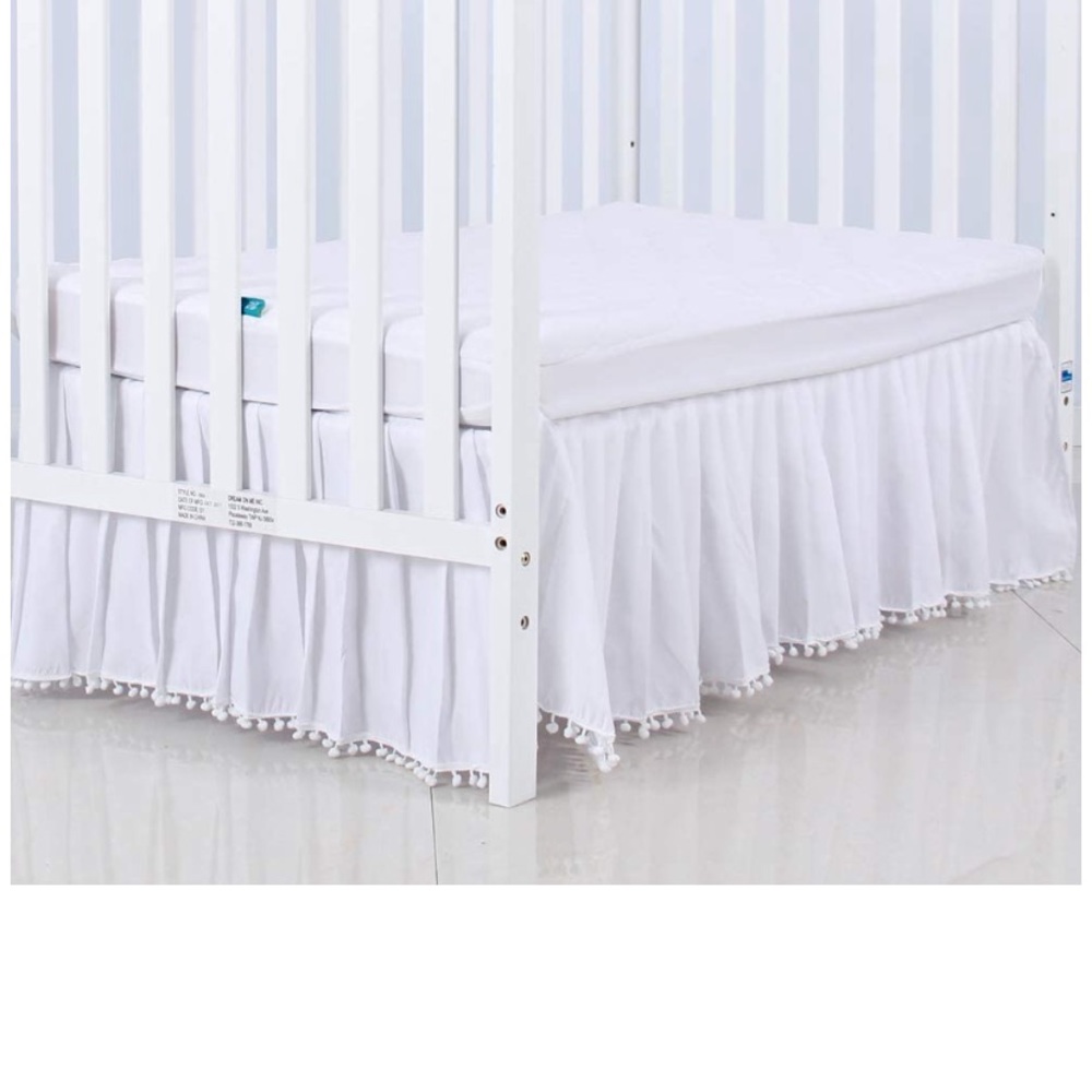 White crib skirt with pom poms